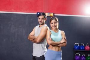 jovem homem e mulher em pé com braços cruzado dentro Esportes roupas às a academia, desportivo casal do amigos às a academia, Esportes e ginástica conceitos foto