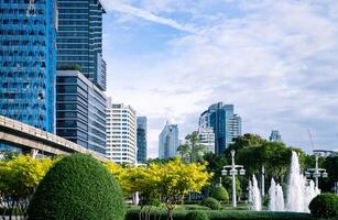 uma cidade com alta escritório edifícios e uma central fonte. sustentável paisagem urbana cercado de árvores e arbustos. sustentável cidade Projeto. urbano ambiente. exuberante cidade parque. dentro uma verde paisagem urbana. foto