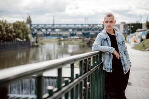 uma homem dentro uma Preto camisa e azul Jaqueta carrinhos em uma ponte grade foto