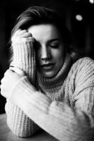 absorta dentro pensamento, uma mulher vestindo uma acolhedor suéter descansos dela cabeça em dela mão, sentado às uma mesa. a imagem captura uma momento do profundo contemplação e introspecção. contemplativo pausa. foto