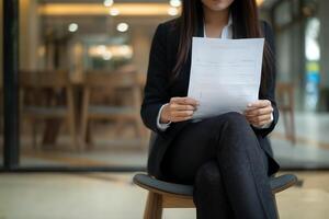 jovem mulher dentro uma terno segurando dela trabalho aplicativo, esperando para a entrevista foto