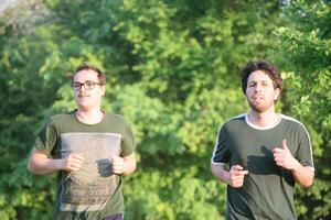 dois amigos corrida com verde camiseta dentro parque foto