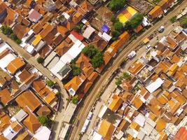 surpreendente panorama do trem faixas. pássaro olho Visão a partir de zangão do uma estrada de ferro linha dentro a meio do densamente populosa casas dentro cicalengka, Indonésia. tiro a partir de uma zangão vôo 200 metros alto. foto