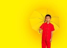 Garoto moda vestindo uma estilo chinês camisa segurando uma amarelo guarda-chuva poses para uma foto atirar.