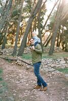 Papai com uma pequeno menina em dele ombros anda em olhando costas ao longo a caminho dentro a floresta foto