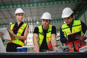 três construção trabalhadores estão em pé por aí uma mesa, olhando às uma computador portátil foto