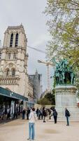 turistas explorando a histórico notre dame catedral com em andamento reconstrução, Próximo para uma estátua dentro Paris, França, capturado em abril 14, 2024, refletindo cultural herança e viagem foto