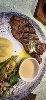 carne Novo Iorque faixa lombo bife ou lombo bife servido com batatas, e cogumelo molho e salada em prato foto