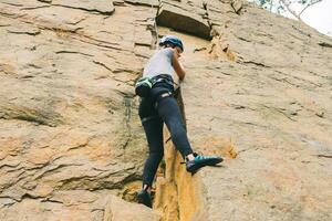 jovem Atlético mulher dentro equipamento fazendo Rocha escalada ao ar livre. Treinamento área para ao ar livre Atividades. extremo esporte. foto