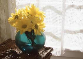 uma vaso com amarelo flores sentado em uma mesa foto