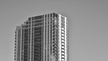 fragmento do a edifício de fachada com janelas e varandas. moderno apartamento edifícios em uma ensolarado dia. fachada do uma moderno residencial prédio. Preto e branco. foto