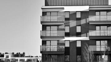 fragmento do a edifício de fachada com janelas e varandas. moderno apartamento edifícios em uma ensolarado dia. fachada do uma moderno residencial prédio. Preto e branco. foto