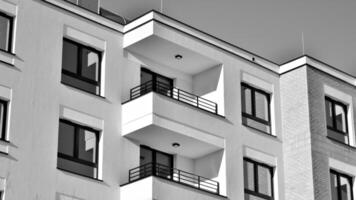 fragmento do a edifício de fachada com janelas e varandas. moderno apartamento edifícios em uma ensolarado dia. fachada do uma moderno residencial prédio. Preto e branco. foto