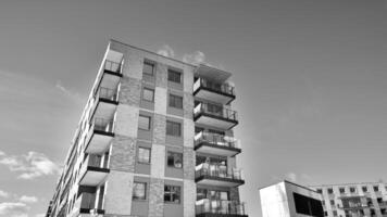 fragmento do a edifício de fachada com janelas e varandas. moderno apartamento edifícios em uma ensolarado dia. fachada do uma moderno residencial prédio. Preto e branco. foto