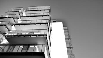 fragmento do uma fachada do uma construção com janelas e varandas. moderno apartamento edifícios em uma ensolarado dia. fachada do uma moderno apartamento prédio. Preto e branco. foto