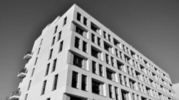 fragmento do a edifício de fachada com janelas e varandas. moderno apartamento edifícios em uma ensolarado dia. fachada do uma moderno residencial prédio. Preto e branco. foto