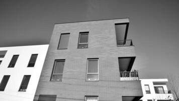 fragmento do a edifício de fachada com janelas e varandas. moderno apartamento edifícios em uma ensolarado dia. fachada do uma moderno residencial prédio. Preto e branco. foto