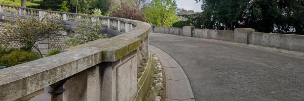 curvado pedra balaustrada ao longo a esvaziar passarela dentro uma sereno parque, evocando tranqüilidade, adequado para temas por aí solidão ou europeu herança jardins foto