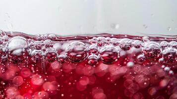 fechar acima do vermelho vinho bolhas dentro uma vidro, macro tomada, isolado em branco fundo foto
