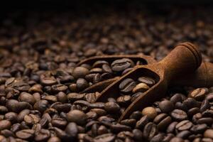 pilha do café feijões com de madeira colher, fechar acima, Sombrio fundo com cópia de espaço, raso profundidade do campo foto