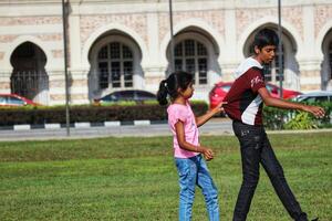 Kuala Lumpur, Malásia em pode 21, 2023. a Mais velho irmão e uma mais jovem irmã estão jogando em a dataran merdeka campo foto