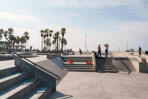 Veneza de praia Parque de skate cena com Palma árvores, skatistas, ensolarado clima dentro Califórnia foto