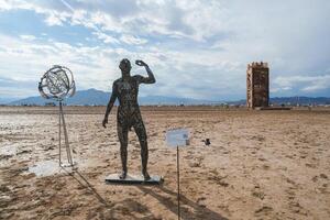 expansivo deserto panorama com humano figura e torre esculturas, festival configuração foto