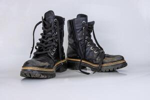 frontal Visão do uma muito desgastado par do botas. velho usava quebrado Preto couro renda Alto botas. na moda tornozelo botas. à moda mulheres masculino unissex grunge chuteiras com cadarço. isolado em branco fundo foto