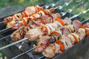 grelhado peças do carne em espetos, shish Kebab com vegetais, cozinhando processo em braseiro foto