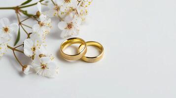 elegante ouro Casamento argolas no meio cereja flores em uma branco pano de fundo foto