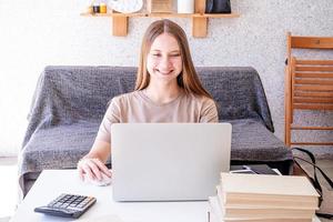 adolescente sorridente estudando usando seu laptop em casa