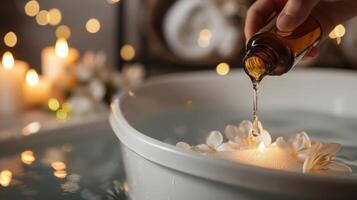 uma mão derramando uma poucos gotas do indulgente perfumado óleo para dentro uma caloroso banho criando uma tranquilo atmosfera foto