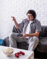 jovem animado jogando videogame em casa apreciando sua vitória foto