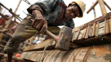 uma fechar-se do uma trabalhador marteladas unhas para dentro de madeira pranchas em topo do andaimes foto