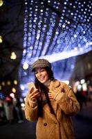 bela jovem usando o celular na rua na época do natal foto