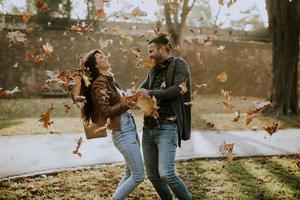 jovem casal se divertindo com folhas no parque outono foto