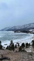 pôr do sol de praia lago baikal com pedras frente e neve a costa baikal dentro inverno foto