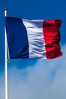 francês tricolor bandeira tremulando com Forte vento e azul céu foto