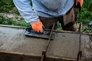 pedreiro espalhando concreto com uma espátula e nível para Construir uma parede às uma construção local foto