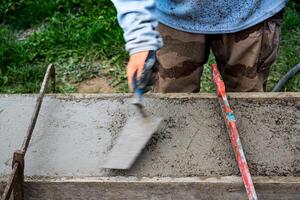 pedreiro espalhando concreto com uma espátula e nível para Construir uma parede às uma construção local foto