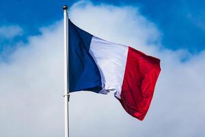 francês tricolor bandeira tremulando com Forte vento e azul céu foto