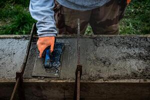 pedreiro espalhando concreto com uma espátula e nível para Construir uma parede às uma construção local foto