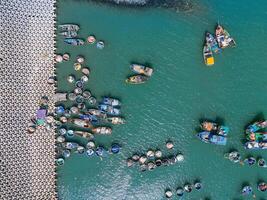 aéreo Visão do loc a pescaria Vila, Vung tau cidade. uma pescaria porta com tsunami proteção concreto blocos. paisagem urbana e tradicional barcos dentro a mar. foto