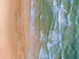 oceano ondas em a de praia Como uma fundo. aéreo topo baixa Visão do de praia e mar com azul água ondas. Vietnã de praia foto