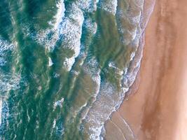 oceano ondas em a de praia Como uma fundo. aéreo topo baixa Visão do de praia e mar com azul água ondas. Vietnã de praia foto