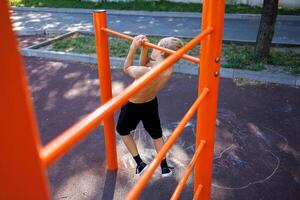 uma adolescente puxa acima em a barra entre Esportes horizontal bares rua exercite-se em uma horizontal Barra dentro a escola parque. foto