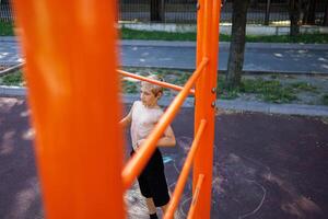 Atlético adolescente obtendo pronto para executar pull-ups em a bar. rua exercite-se em uma horizontal Barra dentro a escola parque. foto