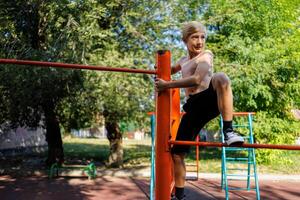 uma Garoto dentro uma escola parque escalou para a topo degrau rua exercite-se em uma horizontal Barra dentro a escola parque. foto