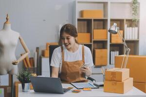 iniciando pequeno o negócio empreendedor sme freelance, retrato jovem mulher trabalhando às casa escritório, caixa, Smartphone, computador portátil, on-line, marketing, embalagem, entrega, b2b, sme, comércio eletrônico conceito.. foto