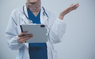 médico vestindo branco casaco e assistindo paciente dados dentro tábua . foto